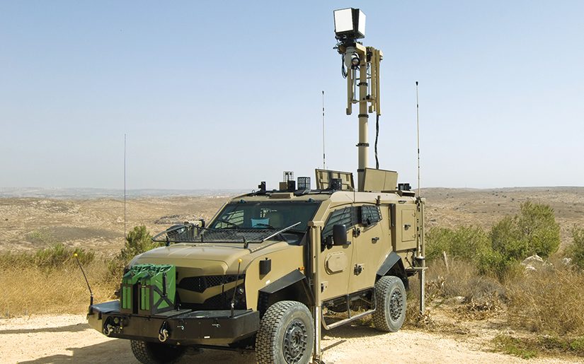 Military truck with an extended sensor mast in dry terrain