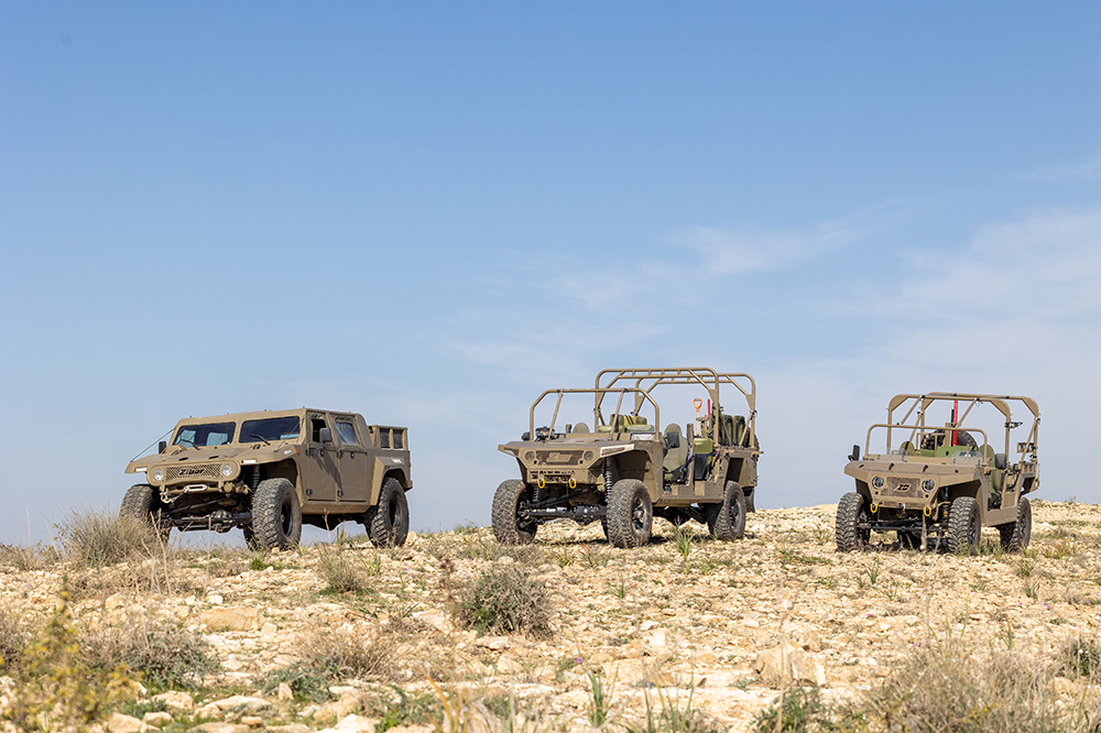 Three light military vehicles in a dry landscape