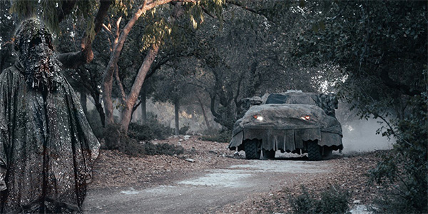 Soldier and vehicle hidden under camouflage covers on a forest road