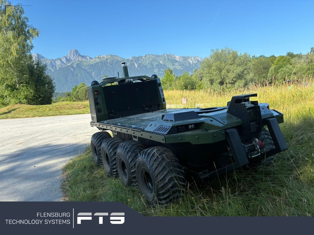 Eight-wheeled unmanned ground vehicle on grass with mountains behind