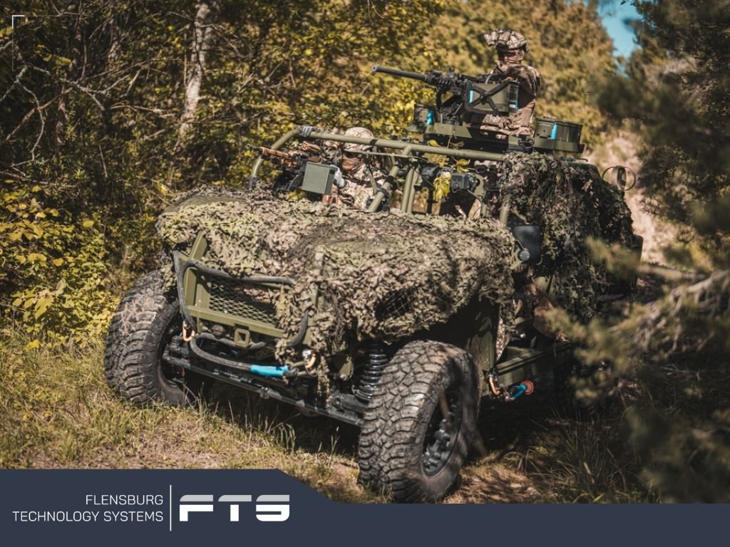 Light military vehicle with camouflage netting in a forest