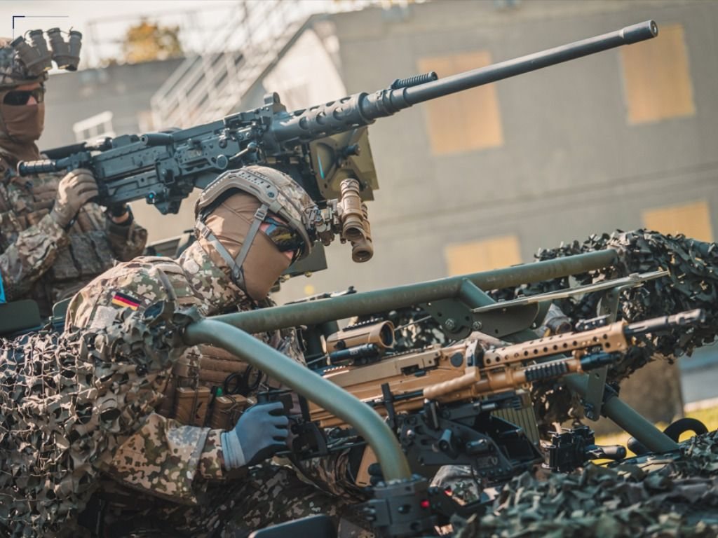 Soldiers operating a mounted weapon on a camouflaged vehicle